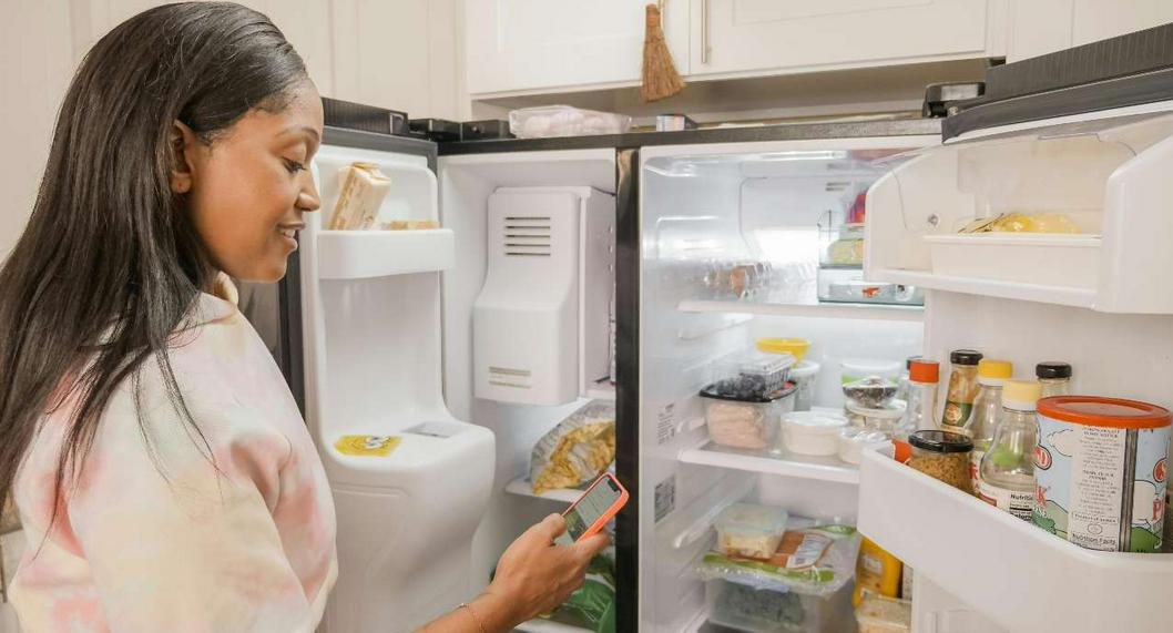 Foto de mujer con refrigerador, en nota de qué no se debe poner arriba de nevera porque podría ser muy peligroso y por qué