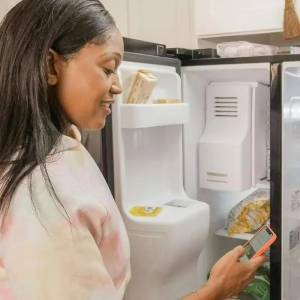 Foto de mujer con refrigerador, en nota de qué no se debe poner arriba de nevera porque podría ser muy peligroso y por qué