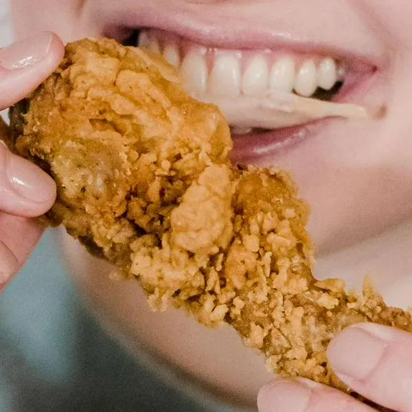 Foto de persona comiendo, en nota de qué tipo de pollo es mejor entre broaster y asado.