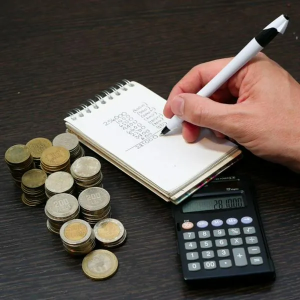 Foto de persona con dinero y calculadora, en nota de cómo invertir la prima en Colombia con planificación, pagos y gasto inteligente