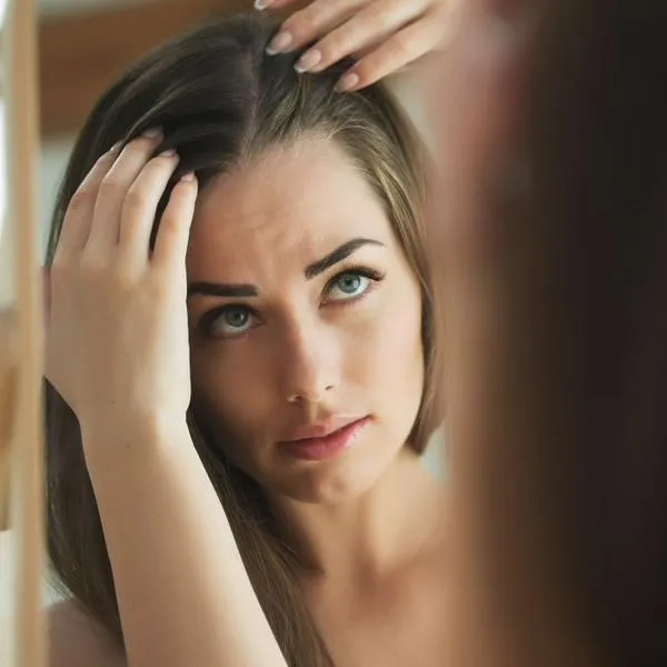 Mujer revisando sus canas, en nota sobre por qué aparecen