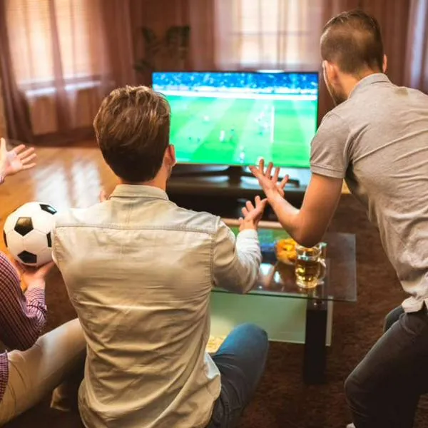 Foto de hombres viendo TV, en nota de cómo poner la TDT en televisor de Colombia para ver goles antes que los vecinos