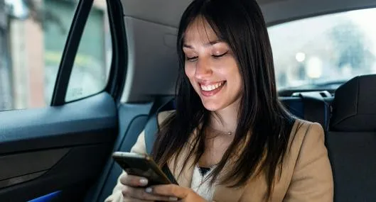 Mujer usando el celular en el carro, en nota sobre cómo no marearse