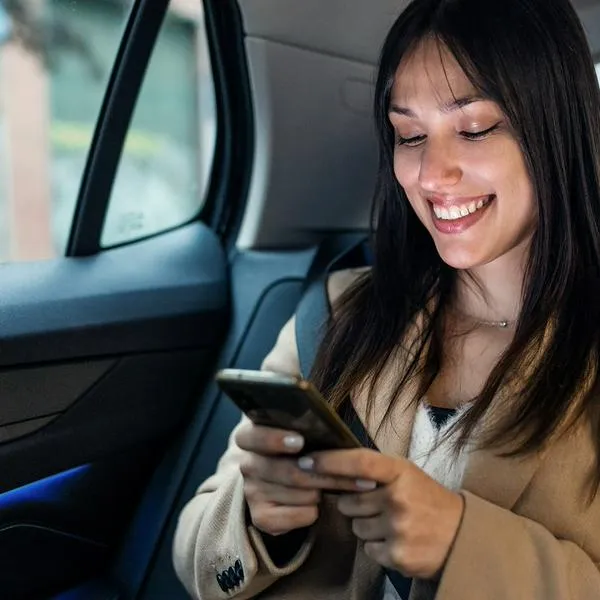 Mujer usando el celular en el carro, en nota sobre cómo no marearse