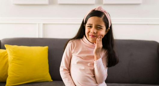 Foto de niña con dolor, en nota de cómo prevenir la caries y reforzar dientes, con medida gratis para niños en Colombia