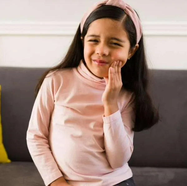 Foto de niña con dolor, en nota de cómo prevenir la caries y reforzar dientes, con medida gratis para niños en Colombia