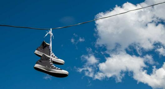 Foto de tenis en calle, en nota de qué significan los zapatos colgados en los cables, según teorías