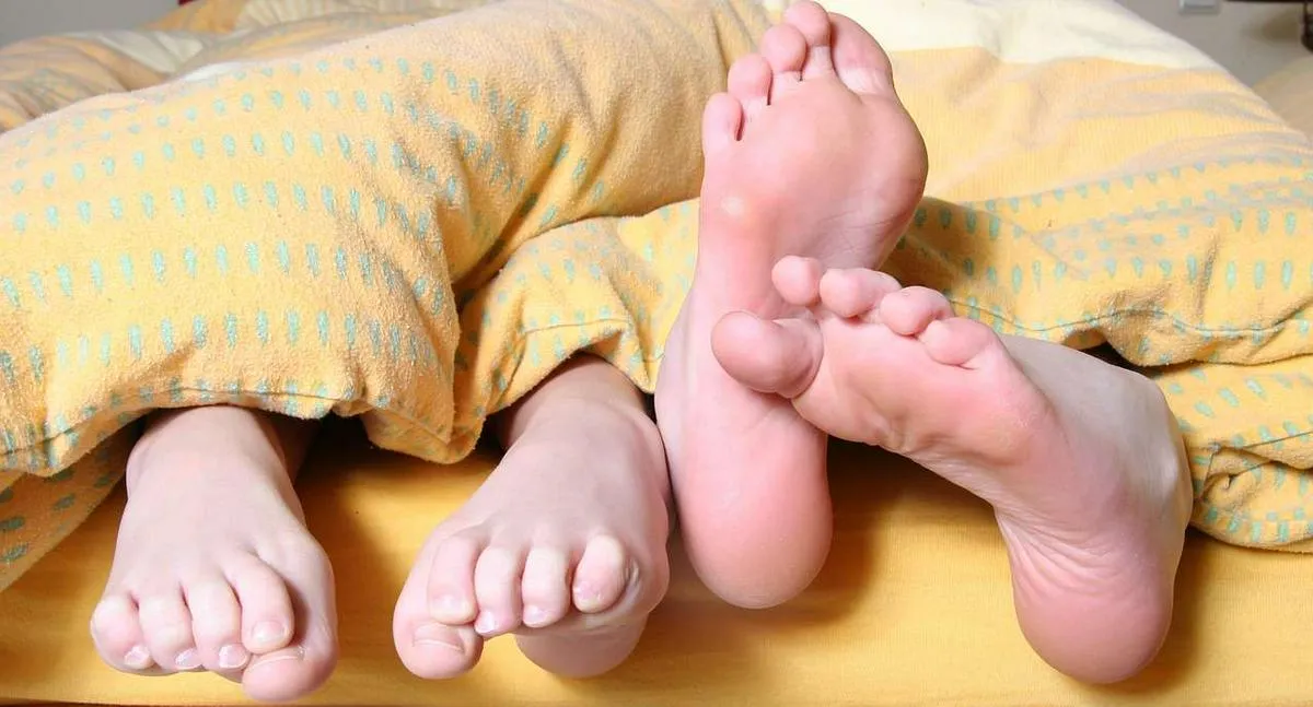 Foto de pies fuera de sábanas, en nota de qué significa dormir con los pies por fuera de la cobija, según la psicología