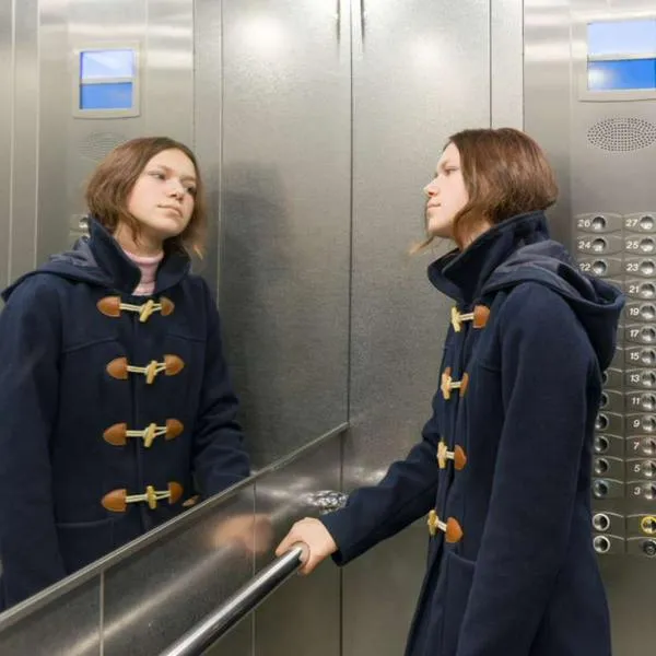 Foto de mujer en ascensor, en nota de qué significa cuando alguien se mira al espejo en el ascensor, según psicología