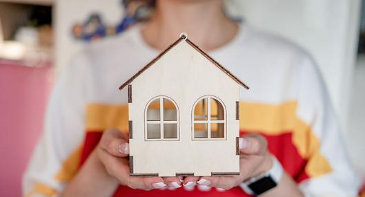 Mujer sosteniendo un modelo de casa, en nota sobre feria de vivienda para mujeres en Bogotá