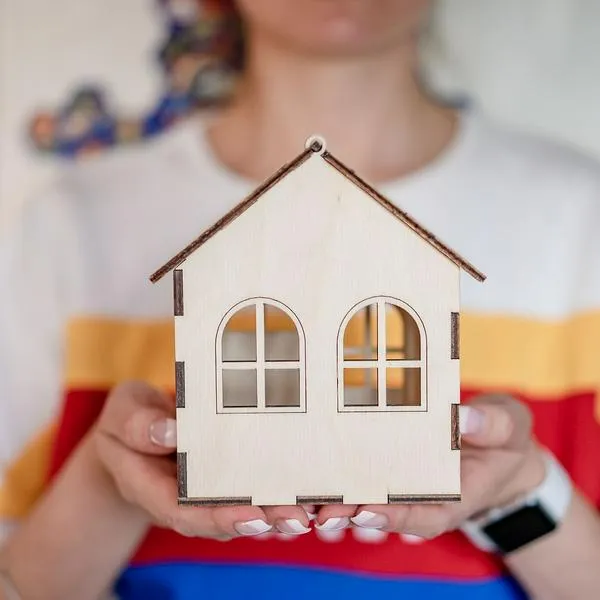 Mujer sosteniendo un modelo de casa, en nota sobre feria de vivienda para mujeres en Bogotá