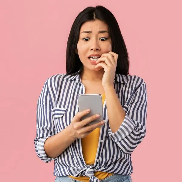 Imagen de referencia de persona asustada viendo su celular.