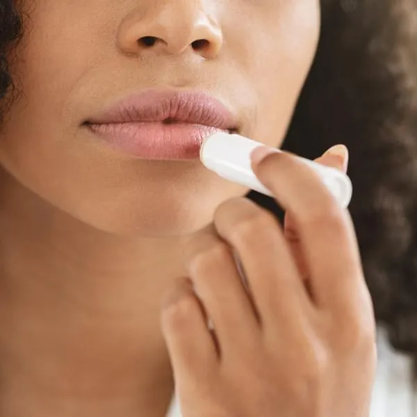 Imagen de referencia de una mujer aplicándose bálsamo labial.