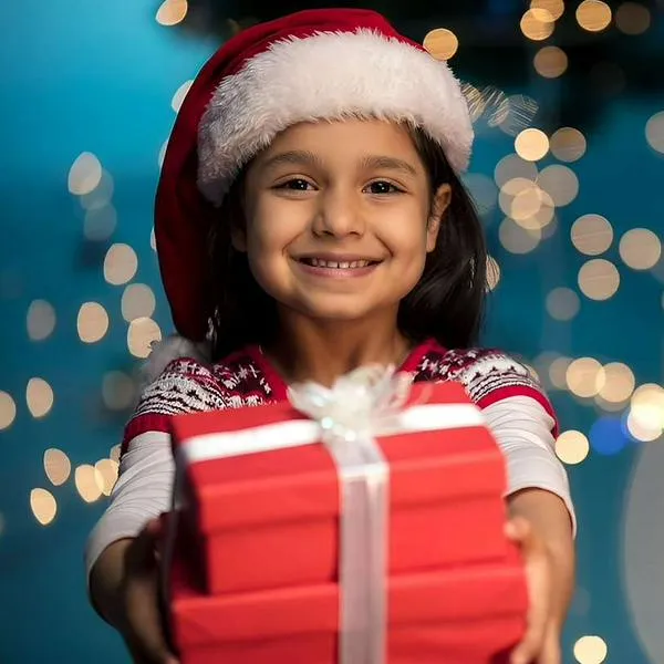 Foto de niña con regalo, en nota de cuáles regalos no son buenos para niños en Navidad, según experta y dice por qué