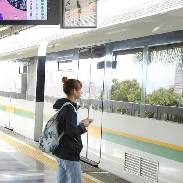 Mujer usando celular en estación del metro de Medellín