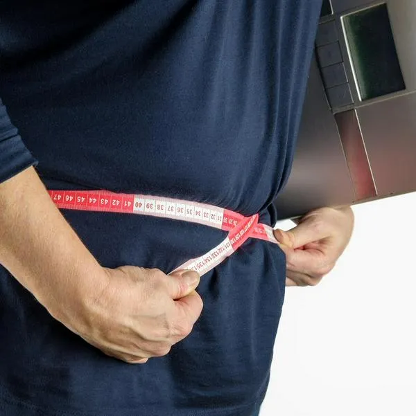Persona midiéndose la barriga, en nota sobre cómo bajar de peso