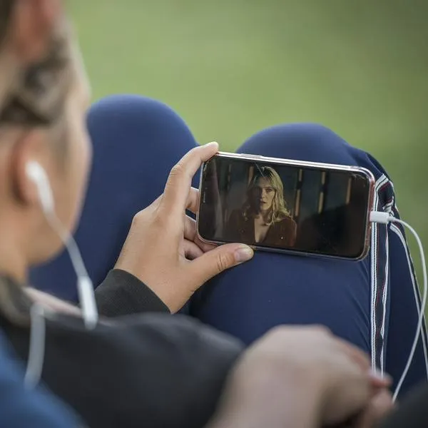 Persona viendo serie en celular, en nota sobre nueva aplicación para ver televisión gratis