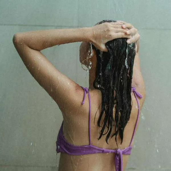 Foto de mujer en ducha, en nota de qué significa bañarse varias veces al día, según psicología.