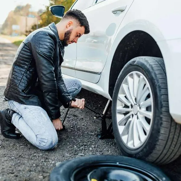 Foto de cambio de llanta, en nota de por qué hay carros que no traen llanta de repuesto: trucos para evitar pinchadas