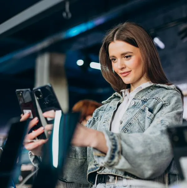 Mujer revisando celulares, en nota sobre qué son los teléfonos reacondicionados y si son confiables