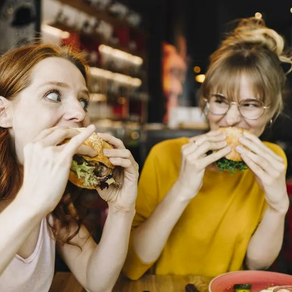 Mujeres comiendo hamburguesa, en nota sobre que McDonald's es la marca de restaurante más valiosa del mundo