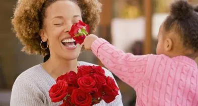 Mujer recibiendo flores de una niña, en nota sobre ciudad de Colombia que tiene un Día de la Madre distinto