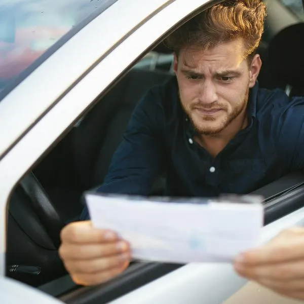 Hombre revisando multa de tránsito, en nota sobre cómo desembargar cuentas o bienes por comparendos