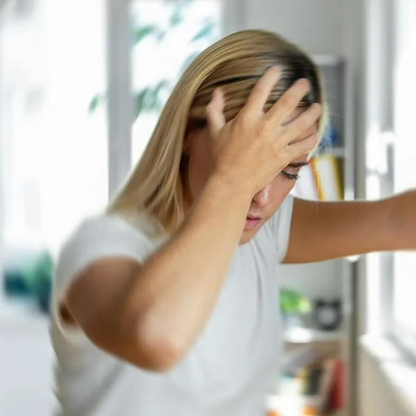 Mujer con dolor de cabeza, en nota sobre síntomas del cáncer cerebral