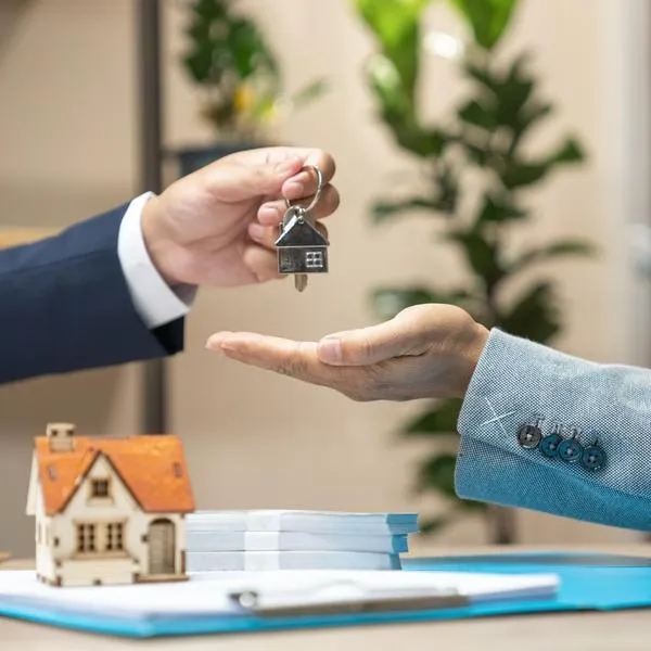 Estate agent giving house keys to woman and sign agreement in office