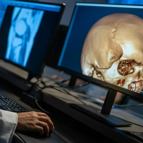 Mid section of female radiologist analysing MRI image of the head and knee on her monitor.