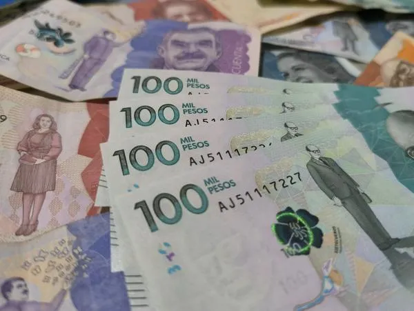 Pesos colombianos y billetes de 100 mil en notas sobre la mesada 14.