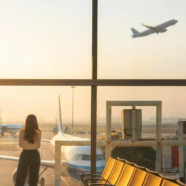 Mujer mirando cómo despega avión, en nota sobre cuál es el vuelo más largo que sale desde Bogotá