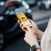 Mujer usando aplicación para pedir taxi, en nota sobre que plataforma colombiana llegó a México
