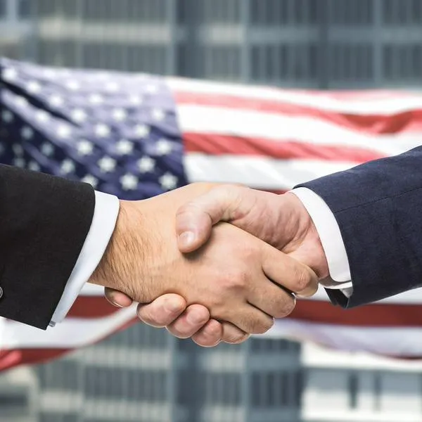 Manos estrechándose encima de bandera de Estados Unidos