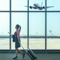 Mujer en un aeropuerto con un avión aterrizando, en nota sobre aerolínea que llegaría a Medellín