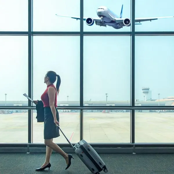 Mujer en un aeropuerto con un avión aterrizando, en nota sobre aerolínea que llegaría a Medellín