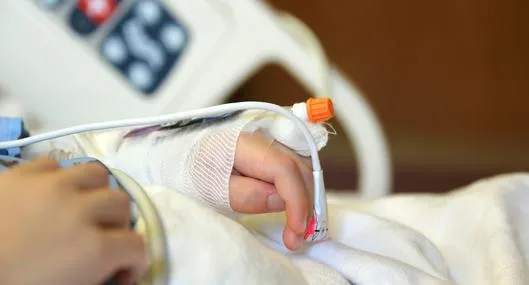 Niño en Medellín quedó en estado crítico por golpiza que le dio su padreA child is laying on a hospital bed with his arm and hand raised above his head with an I.V. and bandage on it.