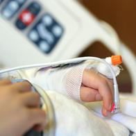 Niño en Medellín quedó en estado crítico por golpiza que le dio su padreA child is laying on a hospital bed with his arm and hand raised above his head with an I.V. and bandage on it.