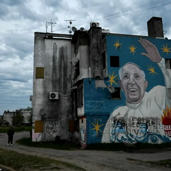 A man walks past mural depicting Pope Francis in the neighborhood where Brenda del Castillo, Morena Verdi and Lara Gutierrez lived in La Tablada, on the outskirts of Buenos Aires, on September 26, 2025. The bodies of Brenda del Castillo (20), Morena Verdi (20) and Lara Gutierrez (15) were found buried in a house in Florencio Varela, on the outskirts of Buenos Aires, on September 24, 2025, five days after their disappearance. The crime, which investigators have tied to narco activity, was perpetrated live on Instagram and watched by 45 members of a private account, officials said. (Photo by Luis ROBAYO / AFP)