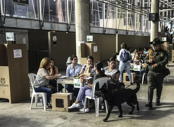 Apoliceman with a sniffer dog patrols a polling station during the presidential runoff election, in Medellin, Antioquia Department, in Colombia on June 17, 2018. - Colombians choose a new president Sunday in a landmark election, the first since a peace agreement with FARC rebels which conservative frontrunner Ivan Duque wants to overhaul. (Photo by JOAQUIN SARMIENTO / AFP)