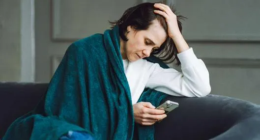 Foto de mujer con celular, en nota de qué significa doomscrolling y por qué es peligroso para cerebro, ojo con celular