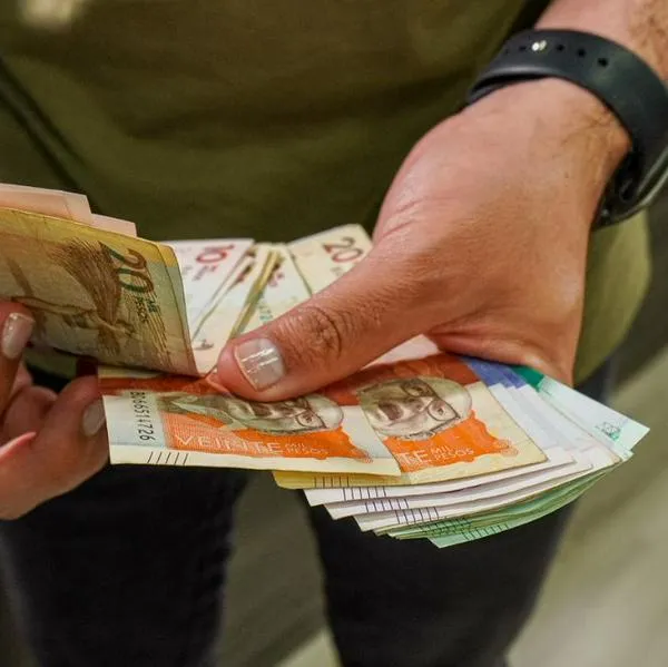 Foto de persona con dinero de Colombia, en nota de que salario mínimo de Colombia en 2026, en alerta por informe de inflación en región