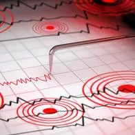 Close-up of a seismograph machine needle tracing seismic waves, indicative of earthquake activity, on graph paper with epicenter rings.