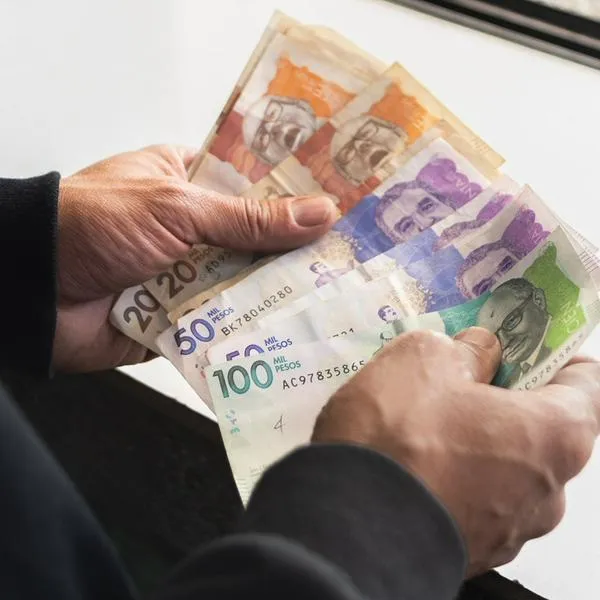 Colombian money, man holding peso bills in front of him, business investments, financial concept