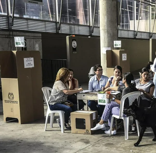 Apoliceman with a sniffer dog patrols a polling station during the presidential runoff election, in Medellin, Antioquia Department, in Colombia on June 17, 2018. - Colombians choose a new president Sunday in a landmark election, the first since a peace agreement with FARC rebels which conservative frontrunner Ivan Duque wants to overhaul. (Photo by JOAQUIN SARMIENTO / AFP)