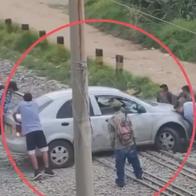 Momento en el que unas personas evitan que un carro, que tenía a su conductor adentro, sea embestido por un tren