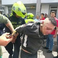 Momento en el que la Policía detiene a un ladrón en Las Ferias, Bogotá, al ser golpeado por ciudadanos que lo vieron hurtando un carro