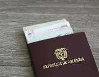 Colombian passport with bank notes over a light grey wooden background