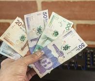 A man holds several Colombian peso bills in his hand.