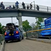 Momento en el que suben un Chevrolet Spark azul en un puente peatonal de Bogotá